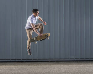 Mann übt Stunt mit Skateboard in der Luft - STSF03235