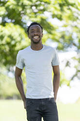 Happy young man standing in park - OCMF02469