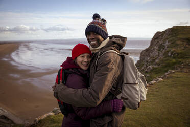 Portrait glücklich. Wanderer Paar umarmt auf Klippe mit Blick auf Strand - CAIF33306