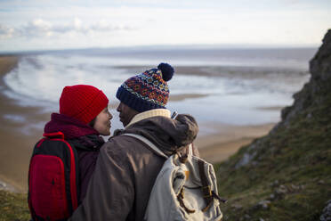 Affectionate couple hiking on cliff with ocean view - CAIF33308