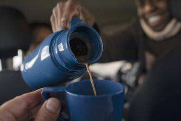 POV Nahaufnahme Mann gießt Kaffee aus Thermoskanne in Tasse - CAIF33317