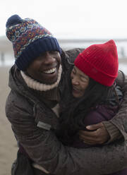 Happy carefree couple in warm clothing hugging - CAIF33319