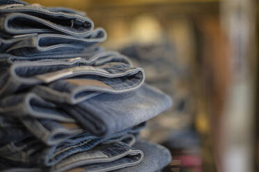 Close up denim jeans stacked in shop - CAIF33329