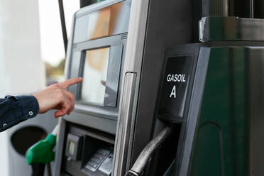 Abgeschnittene, nicht erkennbare Person, die mit Karte an einem Automaten in einer modernen Tankstelle bezahlt - ADSF34865