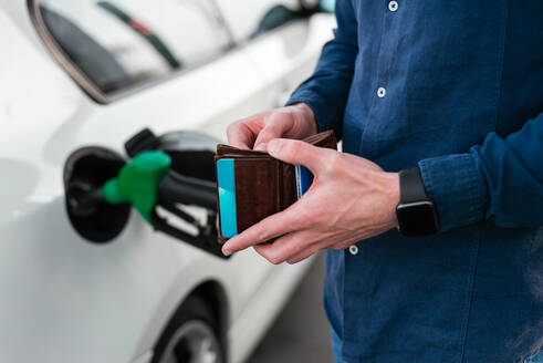 Cropped unerkennbare Person mit Brieftasche und Kreditkarten tanken Auto und zahlen in modernen Tankstelle - ADSF34869