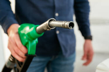 Cropped unrecognizable man refilling vehicle tank at petrol station during energy crisis - ADSF34870