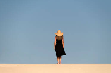 Junge Touristin, die auf einem Sandhügel spazieren geht, während sie die Dünen von Corralejo unter blauem Himmel bei Sonnenuntergang auf den Kanarischen Inseln von Fuerteventura erkundet - ADSF34931
