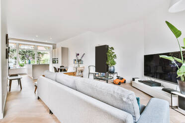 Wohnzimmer mit Sofas und Fernseher und auf der Rückseite ein Esszimmer mit einer modernen Küche mit Schränken mit eingebautem Backofen und eine Insel mit Cerankochfeld und Spüle - ADSF35109