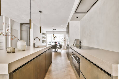 Geräumige Küche mit minimalistischen Möbeln und modernen Einbaugeräten in hellem Studio-Apartment mit Esszimmer - ADSF35135