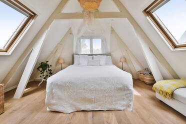 Bright bedroom with several windows on the roof of the house and a double bed decorated with a mosquito net - ADSF35172