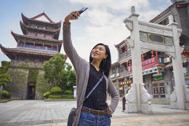 Asiatische junge Frau macht ein Selfie mit Smartphone in einer traditionellen chinesischen Stadt während einer Reise - ADSF35320