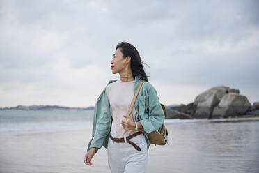 Beautiful Asian girl walking on the beach in Autumn during her trip - ADSF35323