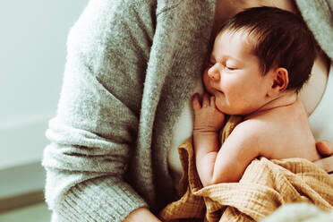 Crop unerkennbar junge Mutter in Freizeitkleidung umarmt und beruhigende entzückende nackte Baby gegen weißen Hintergrund - ADSF35442