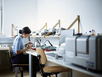 Ingenieur auf einem Stuhl sitzend bei der Arbeit im Elektroniklabor - CVF01985