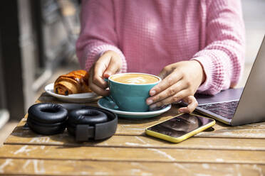 Frau mit Kaffeetasse in einem Straßencafé sitzend - WPEF06049