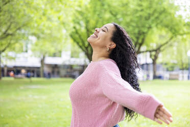 Happy woman with eyes closed enjoying at park - WPEF06073