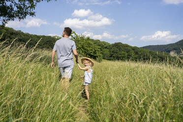 Vater und Tochter gehen an einem sonnigen Tag durch ein Feld - SVKF00298