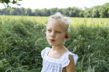 Blond girl wearing cherry earring at field - SVKF00301