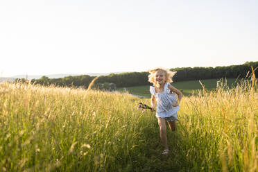 Happy girl running in field - SVKF00322