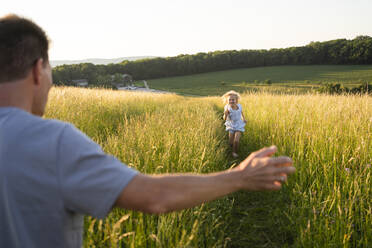 Glückliches Mädchen läuft auf dem Feld auf den Vater zu - SVKF00325