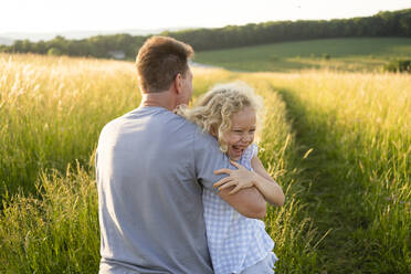 Fröhliche Tochter genießt mit Vater auf dem Feld an einem sonnigen Tag - SVKF00328