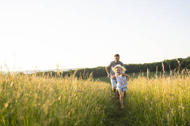 Playful father and daughter running in field - SVKF00331