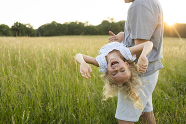 Mature man carrying cheerful daughter enjoying at field - SVKF00334