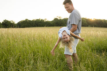 Lächelnder Vater, der seine Tochter trägt und auf dem Feld genießt - SVKF00335