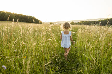 Blond girl walking in green field - SVKF00337
