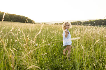 Blond girl walking amidst grass in field - SVKF00338