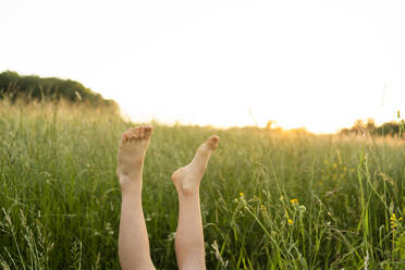 Girl with feet up in field - SVKF00341