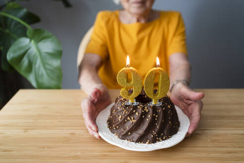 Ältere Frau mit Geburtstagstorte am Tisch sitzend - SVKF00357