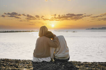 Mother and daughter enjoying sunset at beach - OMIF00925