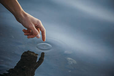 Hand of man touching sea water - OMIF00941