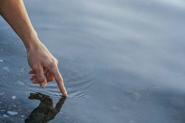 Hand eines reifen Mannes berührt Wasser - OMIF00943