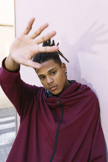 Man showing stop gesture in front of pink wall - MMPF00181