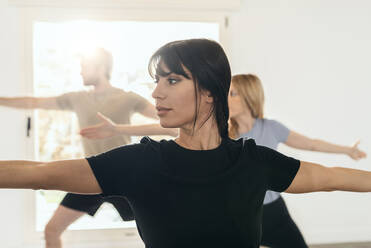 Frau übt Kriegerpose im Yogastudio - JSRF02126