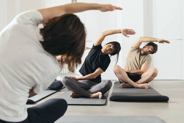 Mann und Frau lernen Yoga von einem Lehrer im Fitnessstudio - JSRF02136