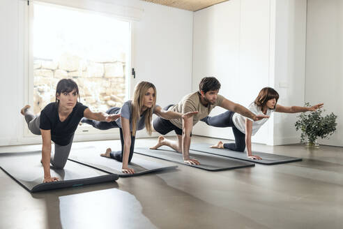 Mann und Frau balancieren beim Üben einer Yogapose im Sportunterricht - JSRF02137