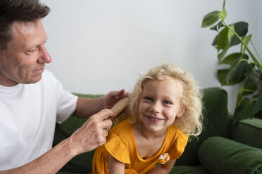 Man combing hair of daughter at home - SVKF00363