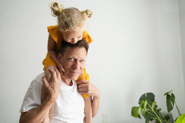 Girl sitting on father's shoulders at home - SVKF00373