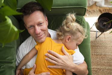 Father lying on sofa with daughter at home - SVKF00378