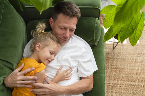 Vater und Tochter entspannen sich auf dem Sofa zu Hause - SVKF00379