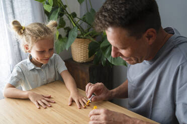 Mann lackiert Nägel seiner Tochter zu Hause - SVKF00384