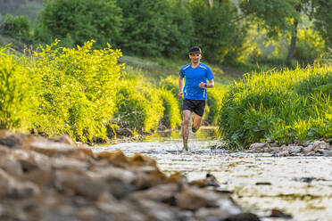 Junger Mann joggt durch den Fluss - STSF03255