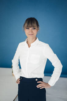 Selbstbewusste Geschäftsfrau vor einer blauen Wand im Büro - JOSEF10790