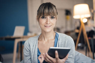 Lächelnde Frau, die zu Hause einen Tablet-PC benutzt - JOSEF10800