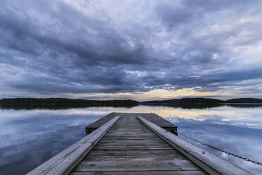 Schweden, Bezirk Vastra Gotaland, Bewölkter Himmel über dem Steg am Ufer des Sees Vastra Silen in der Abenddämmerung - STSF03267