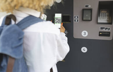 Frau scannt QR-Code am Fahrkartenautomaten - JCCMF06609