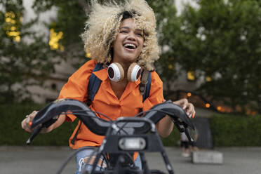 Carefree woman enjoying riding electric bicycle - JCCMF06642